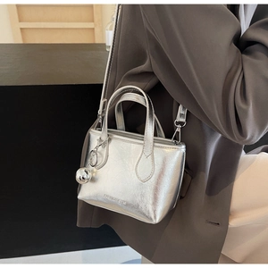 Close-up of silver textured mini bucket bag with metal ball charm and logo detail