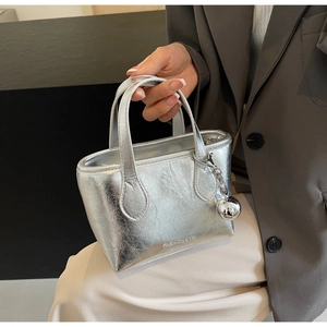 Detail of silver metallic bucket bag with pleated texture and round charm accessory