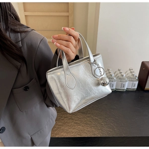 Detail of silver metallic bucket bag with FASHION & YM logo and metal ball pendant