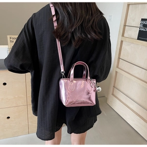 Detailed view of a metallic pink bucket bag with silver sphere charm and brand logo