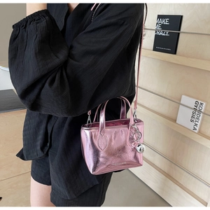 Detail of pink metallic mini tote bag with silver charm shown on a fashion model