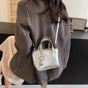 Silver metallic mini bucket bag with crinkled texture and ball charm in lifestyle setting