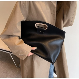 Detail of black faux leather clutch with metal oval handle and embossed logo