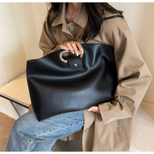 Detail of black matte faux leather tote bag with stylish oval silver metal handle