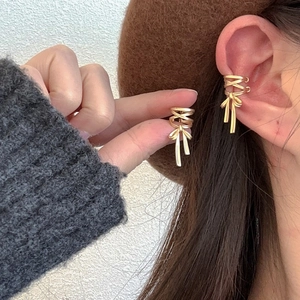 Close-up of golden bow-knot ear cuffs with delicate ribbon design and tassel details