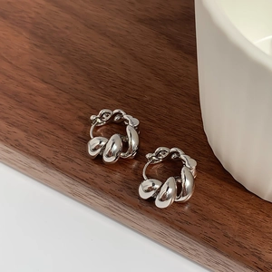 Close-up of silver twist hoop earrings with high-polish finish on a wooden background