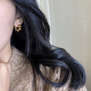 Polished gold twisted hoop earrings with chunky knot design shown on a female model
