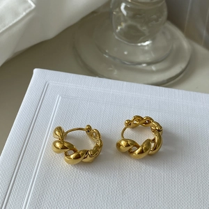 Macro view of gold twisted rope hoop earrings with glossy metallic finish and secure clasp