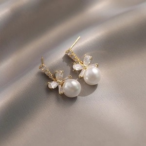 Elegant bow knot pearl drop earrings with sparkling crystals on grey silk background