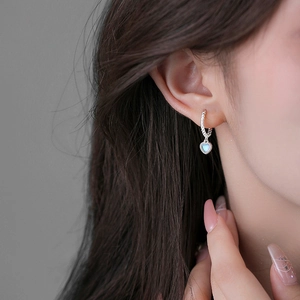 Elegant silver heart moonstone earrings with twisted hoop design on a female model