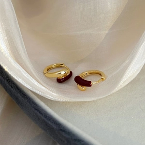 Detail of red enamel huggie earrings with a 18K gold plated finish on silk