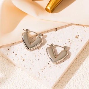 Detailed macro view of silver heart earrings with polished mirror finish and snap closure