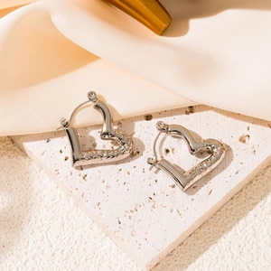 Detail shot of silver heart hoop earrings with textured hammered finish on stone surface