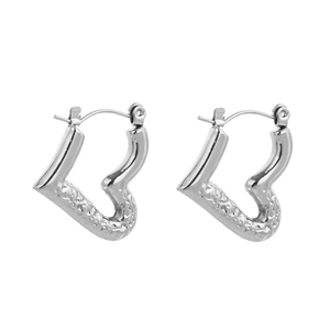 Detailed close-up of heart-shaped earrings featuring a polished and hammered silver finish