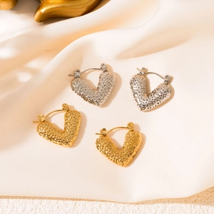 Detail of V-shaped heart earrings in gold and silver with textured hammered finish
