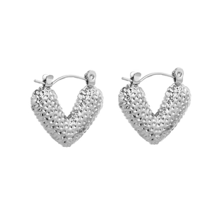Macro shot of silver heart hoop earrings with textured hammered finish and secure latch back