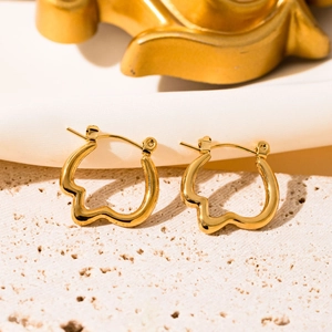 Close-up of golden wavy polygon hoop earrings with mirror finish on stone base