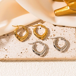Detail of gold and silver crescent earrings with textured ridges on travertine stone