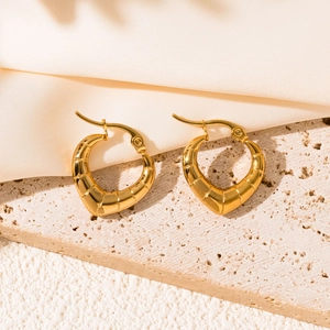 Detail of gold heart-shaped earrings with unique horizontal textured finish on stone