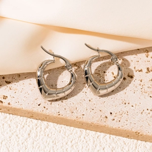 Macro shot of silver heart-shaped hoop earrings with textured horizontal grooves