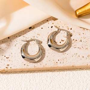 Macro view of silver crescent hoop earrings with a mirror-polished stainless steel finish