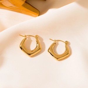 Macro shot of geometric gold titanium steel earrings with a polished mirror finish detail