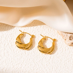 Detail of twisted 18K gold plated stainless steel hoop earrings with mirror finish