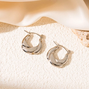 Detail shot of silver twisted hoop earrings with a metallic finish on a textured base