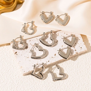 Polished and hammered silver heart hoop earrings set displayed on a stone surface