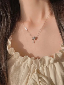 Macro detail of silver sterling necklace with zircon pendant and side letter charm