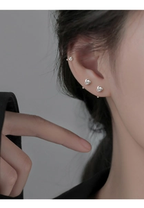Gros plan de boucles d'oreilles nœud Ruyi argenté montrant les détails tissés