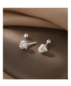 Gros plan de boucles d'oreilles nœud en argent avec texture tissée sur soie élégante