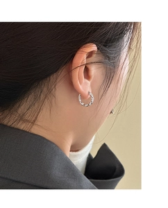 Gros plan de boucles d'oreilles créoles torsadées en argent avec zircons sur un modèle