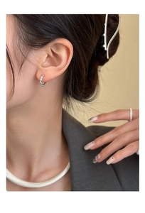 Gros plan de boucles d'oreilles créoles en argent serties de zircons sur un mannequin