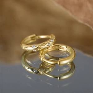 Macro view of 925 sterling silver star hoop earrings with gold plating and zircons