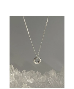 Gros plan d'un pendentif rond argenté sur une chaîne fine avec cristaux blancs
