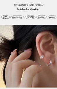 Detail of irregular wave texture on silver hoop earrings worn on helix and lobe