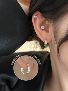Detail of silver Mobius loop earrings with a twisted double-layer texture on the model