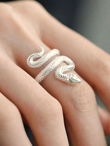 Macro detail of silver snake ring with green gemstone eyes and textured scales