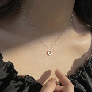 Collier minimaliste en argent S925 avec pendentif cercle sur le décolleté d'une femme élégante