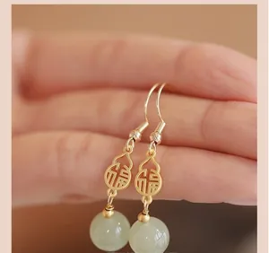 Macro view of gold gourd earrings with Fu character and green jade stone beads