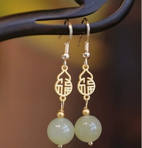 Macro view of gold gourd earrings with Chinese Fu character and green jade beads