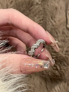 Dettaglio di un anello regolabile in argento con zirconi su uno sfondo di peluche