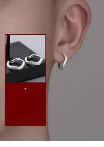 Macro detail of wave-shaped S925 sterling silver earrings with matte textured finish