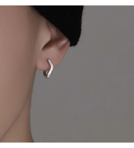 Detailed macro shot of a wave-shaped matte S925 silver hoop earring on an ear