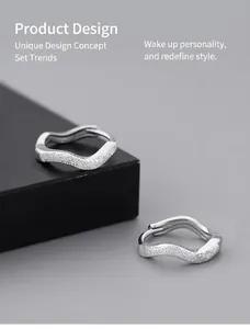 Macro shot of wave-shaped S925 silver hoop earrings with a matte frosted texture finish
