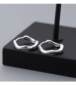 Macro detail of wave-shaped S925 sterling silver earrings with a mirror polished finish
