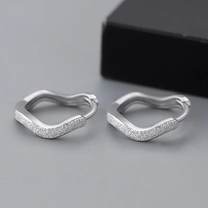 Macro detail of silver S925 sterling silver hoop earrings with frosted matte finish