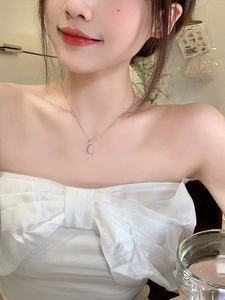 Dettaglio di una collana con ciondolo a goccia d'argento minimalista sul collo di un modello