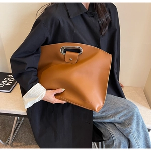 Detail of caramel leather handbag featuring a round metal handle and ORIGINALLY logo